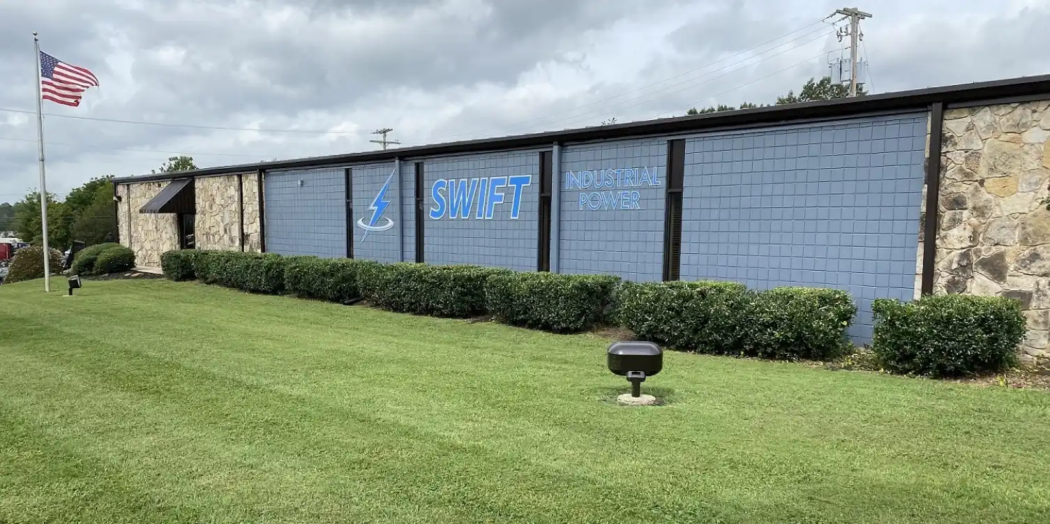 A lawn with bushes and a sign for swift industrial power.